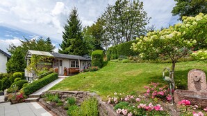 A residential property with a well-maintained lawn, a stone pathway, and a variety of flowering plants. - Apartment 'Ferienhaus Doris' with Mountain View, Private Terrace and Wi-Fi (Willingen (Upland))