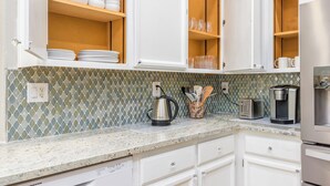 A kitchen with white cabinets, a granite countertop, a coffee maker, a toaster, and a dishwasher. - Charming 3Q Home w/Gourmet Backyard in Elk Grove (Elk Grove)