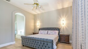 A bedroom with a tufted bed, two bedside tables, a ceiling fan, and a window with an arched doorway. - Charming 3Q Home w/Gourmet Backyard in Elk Grove (Elk Grove)