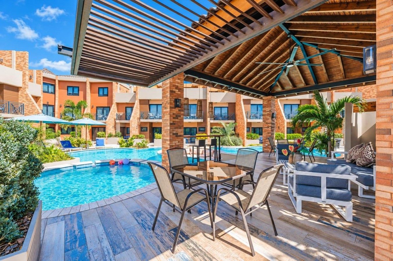 A poolside area with a pool, lounge chairs, and a covered seating area.