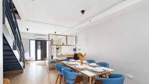A modern dining area with a table set for four, blue chairs, and a staircase on the left. - LUX 3BR House Pool Gym 7-Min Walk Palm Beach - Porta Al Sole 7 by Bocobay (Noord)