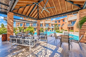 A covered outdoor area with a pool, lounge chairs, and a dining table.