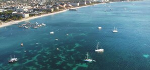 An aerial view of a coastal city with a marina, boats, and buildings along the shoreline. - LUX 3BR House Pool Gym 7-Min Walk Palm Beach - Porta Al Sole 7 by Bocobay (Noord)
