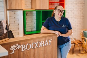 A reception desk with the name 'BOCOBAY' and a logo of a tree. - LUX 3BR House Pool Gym 7-Min Walk Palm Beach - Porta Al Sole 7 by Bocobay (Noord)