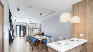 A modern dining area with a white table, blue chairs, and a wooden accent wall. - LUX 3BR House Pool Gym 7-Min Walk Palm Beach - Porta Al Sole 7 by Bocobay (Noord)