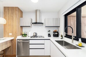 Une cuisine moderne avec des meubles blancs, des appareils en acier inoxydable et un robinet noir.