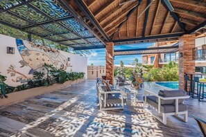 A covered outdoor area with a pool, seating, and a decorative wall.