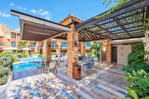 A rooftop pool area with a covered seating area, poolside chairs, and a view of the building's exterior. - LUX 3BR House Pool Gym 7-Min Walk to Palm Beach - Porta al Sole 4 by Bocobay (Noord)