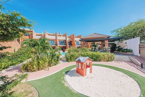 Un resort con piscina, casa de juegos infantil y jardín ajardinado.