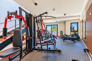 A gym with various exercise equipment, including a bench press, weight machines, and cardio machines. - LUX 3BR House Pool Gym 7-Min Walk to Palm Beach - Porta al Sole 4 by Bocobay (Noord)