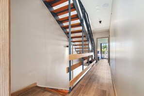 Ein modernes Interieur mit einer Holztreppe und einem Flur, der zu einer Tür führt.