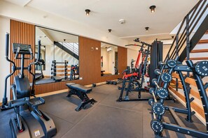 Une salle de sport équipée de matériel d’exercice, d’un banc et d’un miroir.