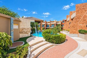 Ein Poolbereich eines Resorts mit blauem Himmel, einer Steinsäule und einer Poollandschaft.