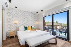 Ein Schlafzimmer mit einem großen Bett, einer Bank, einem Nachttisch, einer Topfpflanze und Blick auf einen Pool und eine Außenlounge.