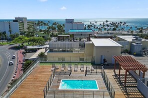 Ein Pool auf dem Dach mit Blick auf den Ozean, umgeben von Palmen und Gebäuden.