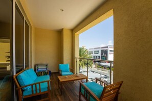 Un balcon doté de mobilier en bois, comprenant une table et deux chaises, et offrant une vue sur un paysage urbain avec des bâtiments et des palmiers.