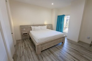 Ein Schlafzimmer mit einem hölzernen Bett, einem Nachttisch und einem Fenster mit Vorhängen.