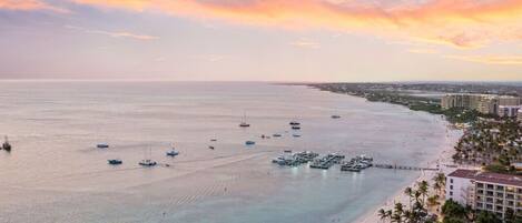 Une vue sur la côte, avec un port de plaisance, une plage et des bâtiments d’hôtel.