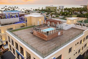 A rooftop with a pool, a bar, and a view of the ocean.
