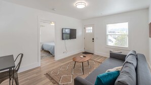 A modern living room with a gray sofa, a small wooden coffee table, and a TV mounted on the wall.