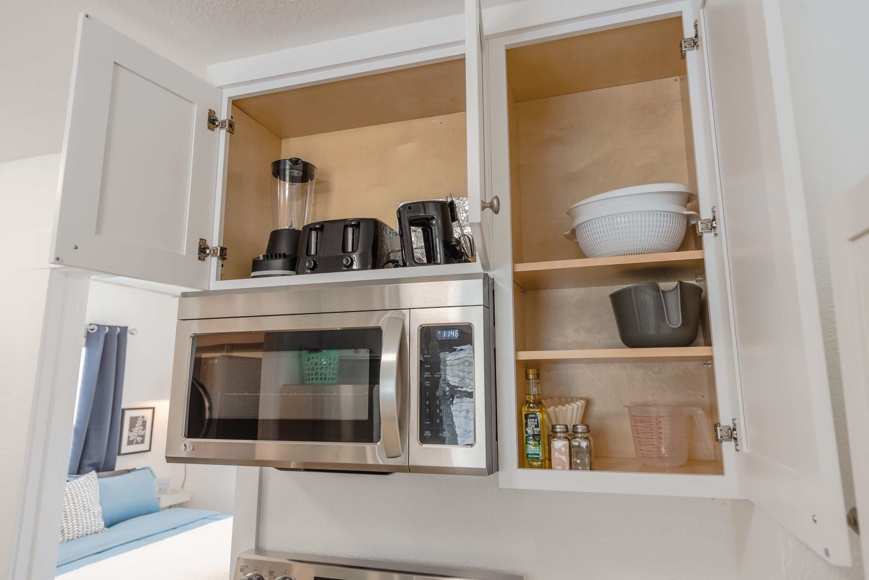 A kitchen with a built-in microwave and oven, a coffee maker, and various kitchen utensils and containers.