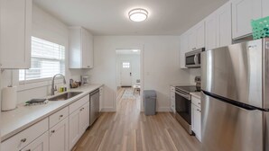 Une cuisine moderne avec des meubles blancs, des appareils en acier inoxydable et un plancher en bois.