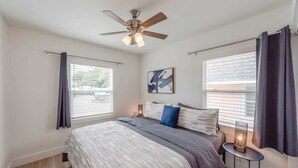 Une chambre à coucher avec un lit, un ventilateur de plafond et une table de chevet avec une lampe.