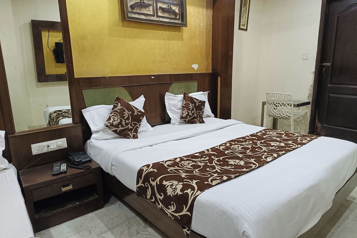 A hotel room with a bed, a nightstand, a phone, and a chair.