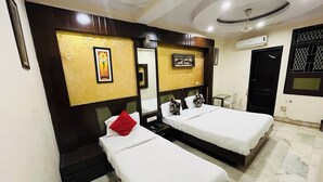 A hotel room with two single beds, a small table, a chair, and a ceiling fan. - Hotel Spot Inn Paharganj Near New Delhi Railway Station (New Delhi)
