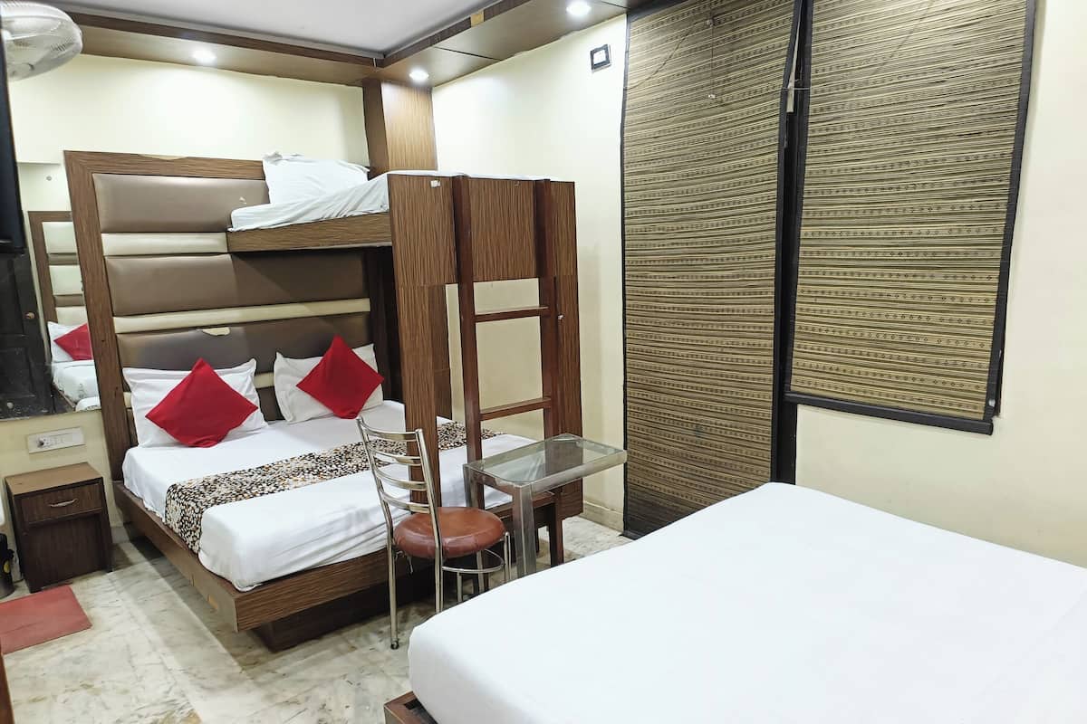 A hotel room with a bunk bed, a small table, and a single bed.