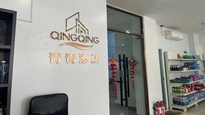 A hotel interior with a reception desk, a wall-mounted sign, and shelves stocked with bottled water and beverages. - Qingqing Hotel Pasay Manila near MOA (Pasay)