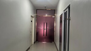 A hallway with a purple door, a security camera, and a glass door on the right. - Qingqing Hotel Pasay Manila near MOA (Pasay)