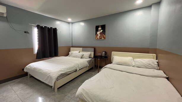 A hotel room with two beds, a small table, a wall-mounted artwork, and a window with curtains. - Qingqing Hotel Pasay Manila near MOA (Pasay)