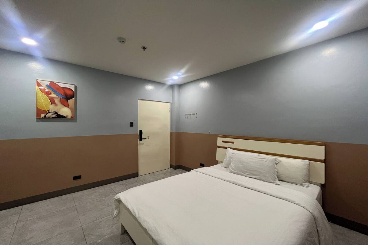 Ein Hotelzimmer mit einem Bett, einer Tür und einem an der Wand befestigten Kunstwerk.