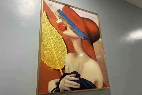 A framed artwork featuring a person holding a large yellow leaf. - Qingqing Hotel Pasay Manila near MOA (Pasay)