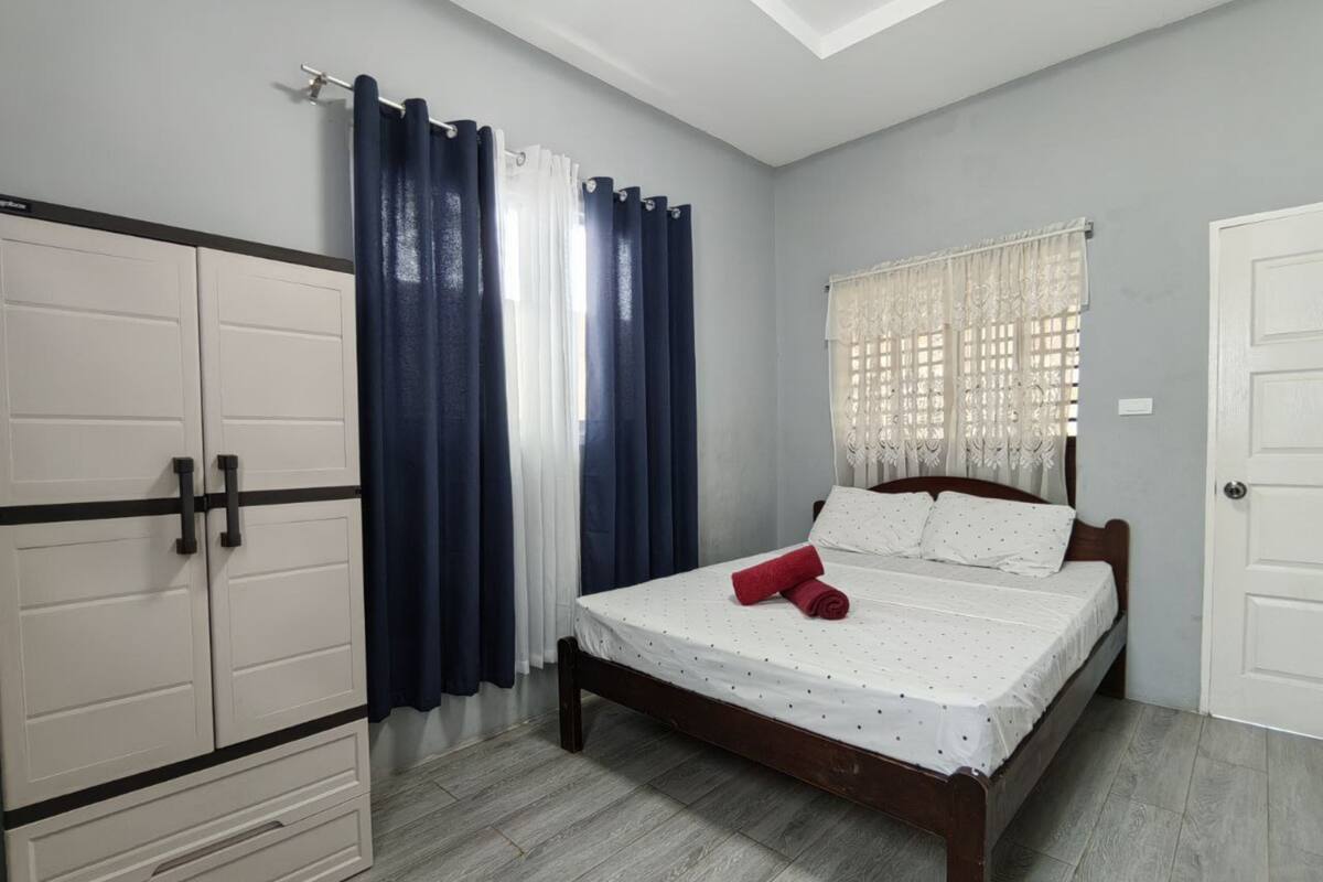 Une chambre à coucher avec un lit, une armoire et une fenêtre avec des rideaux.