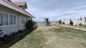 A residential property with a covered patio, a grassy yard, and a view of the sea. - Sea Breeze Beachfront Villa Cebu (Argao)