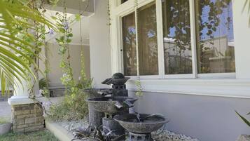 A stone water feature with multiple tiers in front of a building with a window.