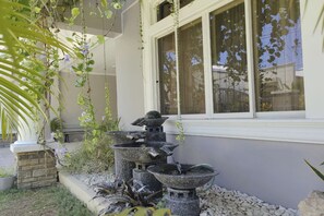 A stone water feature with multiple tiers in front of a building with a window.