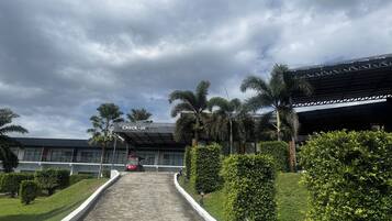 A pathway leading to a building with a 'Check-in' sign, surrounded by greenery and palm trees.