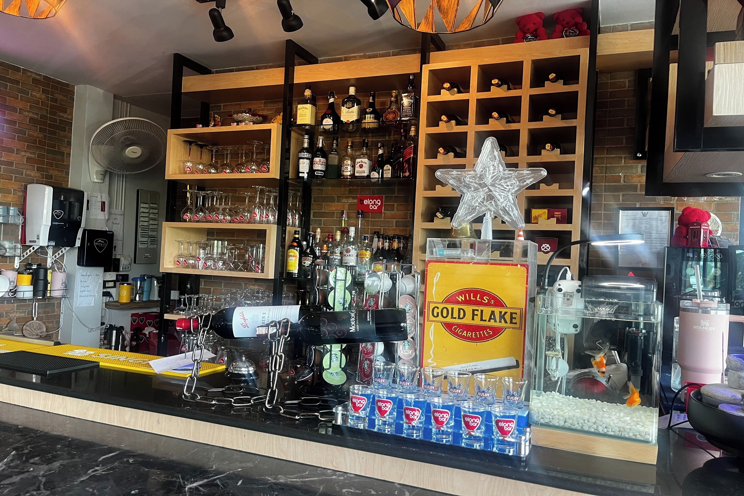 A bar area with shelves of liquor bottles, a star decoration, and a fish tank with goldfish.