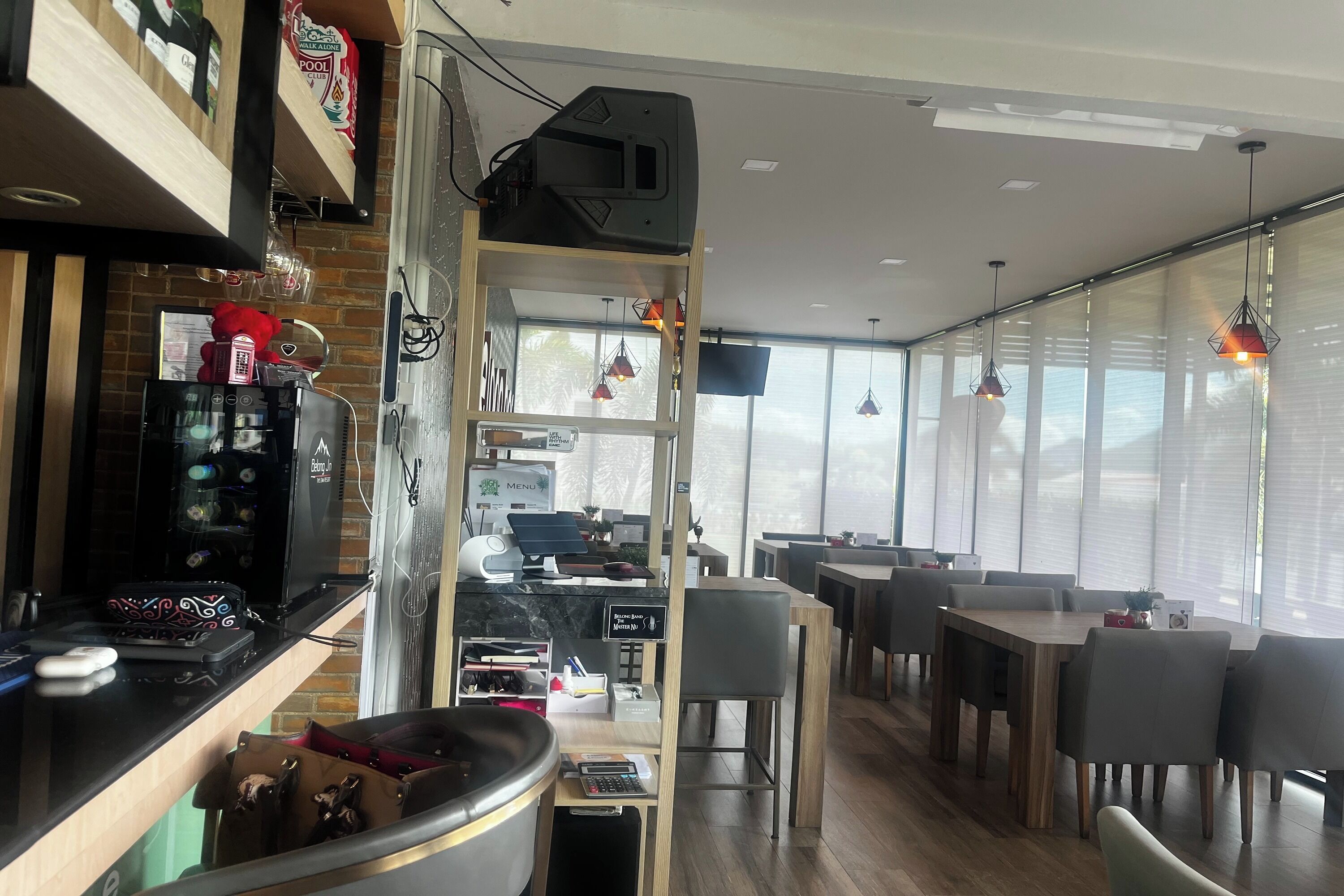 A modern restaurant with a bar area, dining tables, and a counter with a menu display.
