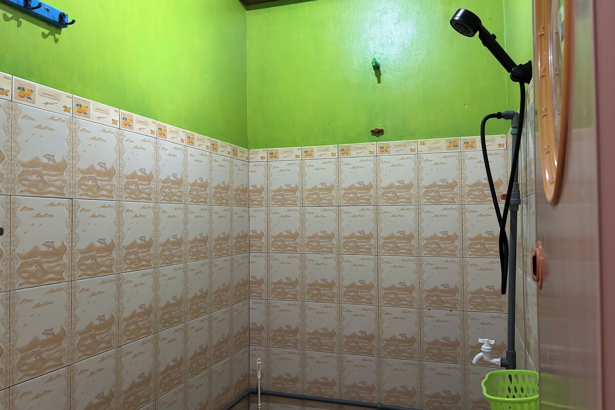 Ducha en esquina con paredes verdes y azulejos estampados.