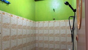 A corner shower with green walls and patterned tiles. - Family 24 Hotel near Pantai Cipatujah (Cipatujah)