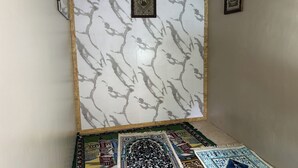 A room with a marble-patterned wall, a framed decorative item, and a patterned carpet. - Family 24 Hotel near Pantai Cipatujah (Cipatujah)