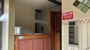 A reception desk with a wooden finish, a reception sign, and a window with bars. - Family 24 Hotel near Pantai Cipatujah (Cipatujah)