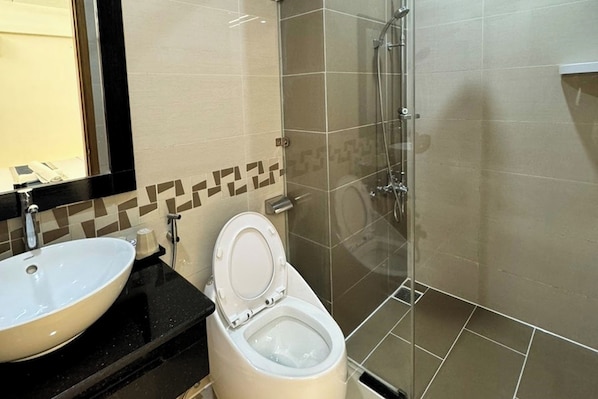 A bathroom with a white sink, a toilet, and a shower area.