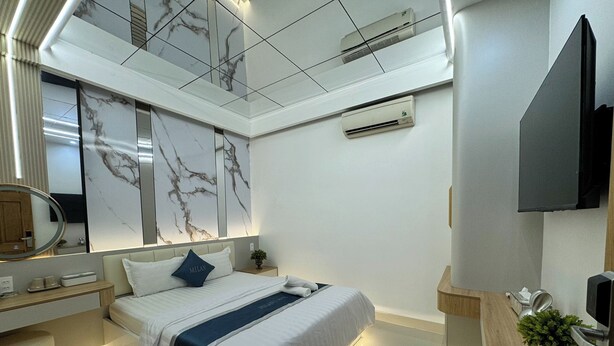 Una habitación de hotel moderna con una cama, mesita de noche y un espejo grande.