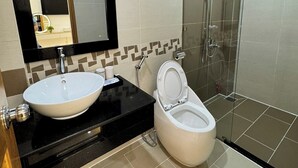 Un baño moderno con un espejo grande, un lavabo blanco y una ducha con cerramiento de vidrio.