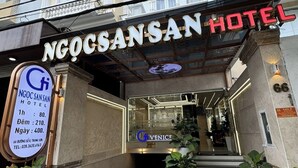 La entrada del Hotel NgoCsansan, con un cartel que muestra tarifas de habitaciones e información de contacto.
